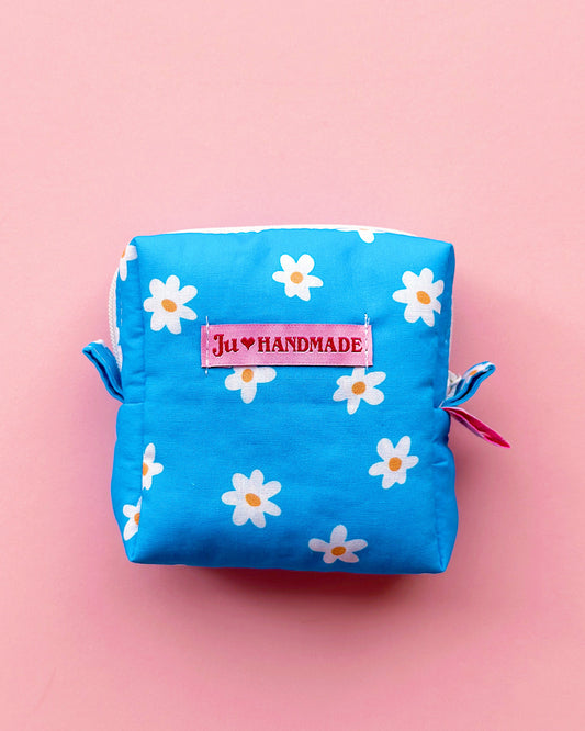 a cute cube shape blue daisy with YKK zipper pouch in a pink background