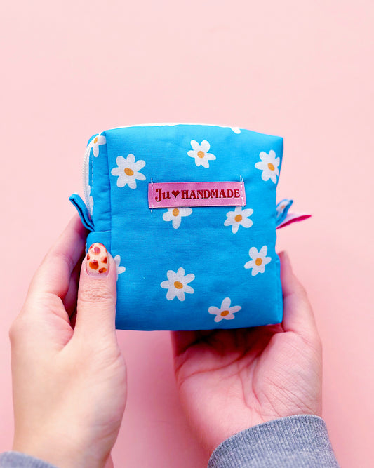 a cute cube shape blue daisy with YKK zipper pouch in a pink background