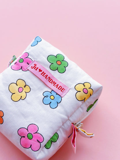 a cute colorful daisy zip up make up bag with "theJU" pink woven label