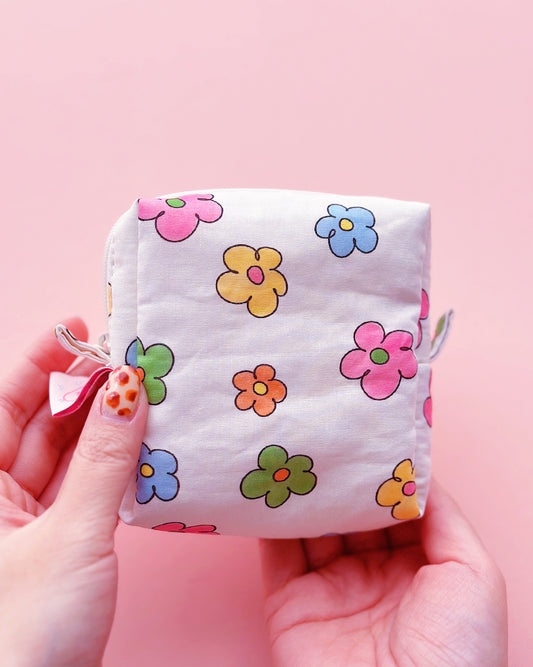 a cute colorful daisy zip up make up bag in a pink background
