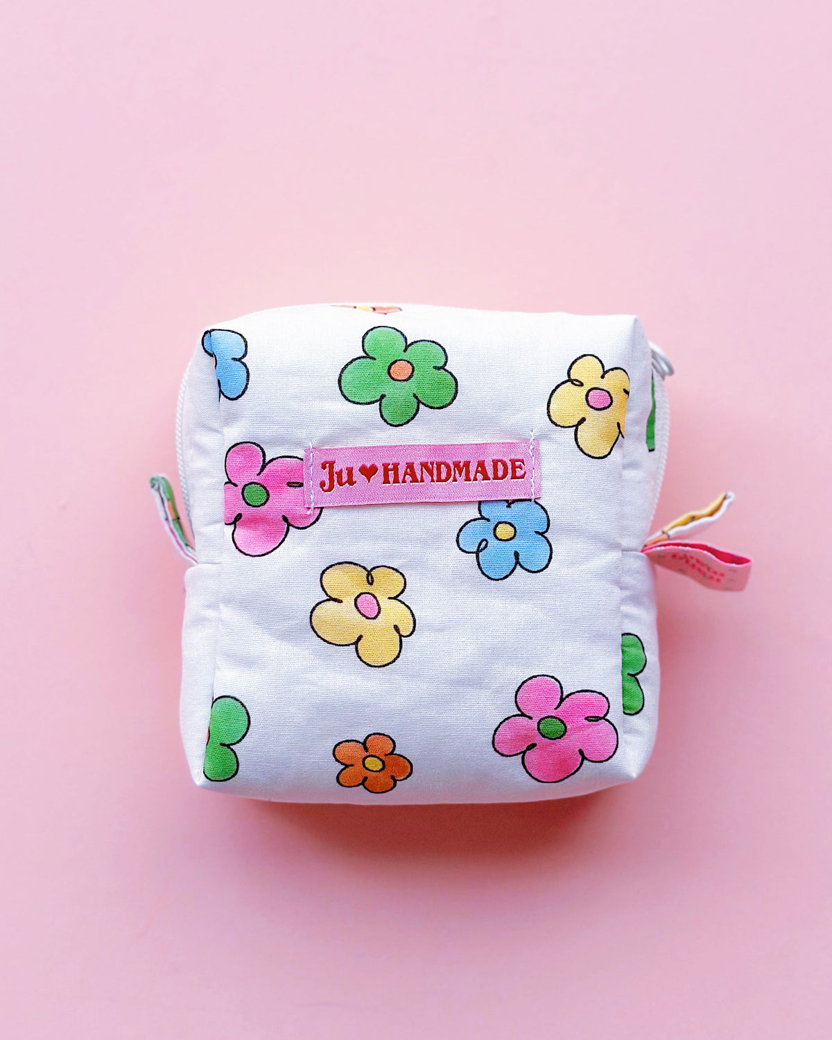 a cute colorful daisy zip up make up bag in a pink background