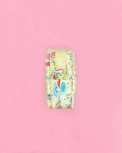 Handmade fairy tale mushroom print quilted zipper pouch with ruffled lace trim, boxy 10×10×5cm design on a pink background.