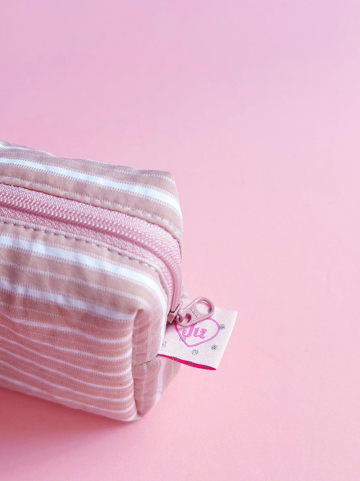 a close up view of pastel brown striped zip pouch for make up and camera 